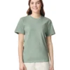 Smiling young woman wearing a sage green T-shirt and beige pants, standing against a white background.