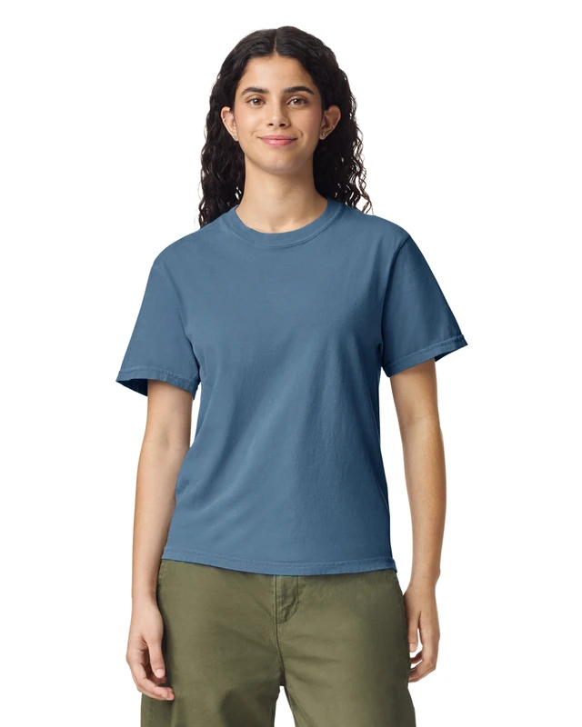 Woman wearing a blue crew-neck T-shirt and olive-green pants, standing and facing the camera with a neutral smile.