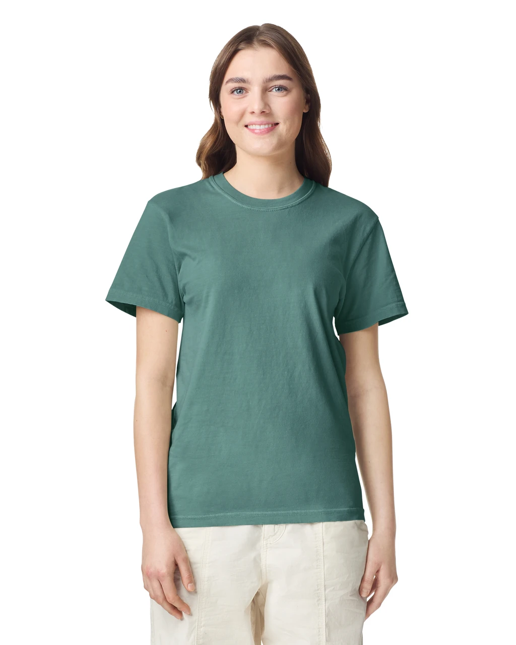 Woman wearing a teal short-sleeve crew-neck T-shirt and light pants, smiling against a white background.