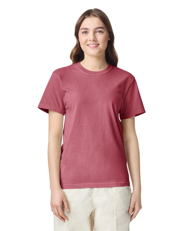 Woman in a plain rose-colored short-sleeve T-shirt, smiling at the camera against a white background.