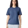 Woman with curly hair wearing a blue T-shirt and light gray sweatpants, smiling against a white background.