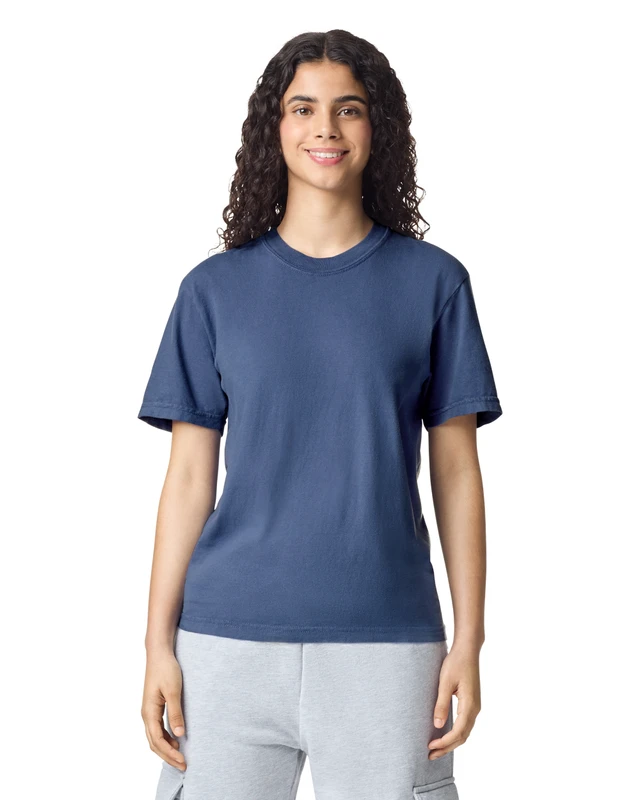 Woman with curly hair wearing a blue T-shirt and light gray sweatpants, smiling against a white background.