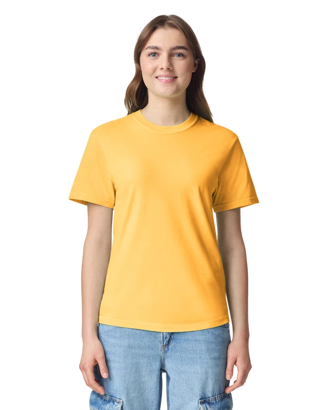 Smiling woman wearing a bright yellow T‑shirt and light blue jeans, standing against a white background.
