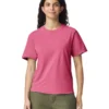 Woman wearing a pink t-shirt and olive-green pants, standing and smiling against a white background.
