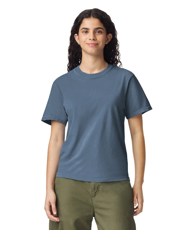 Woman wearing a blue short-sleeve crew-neck T-shirt and olive green pants, facing forward with a neutral smile.