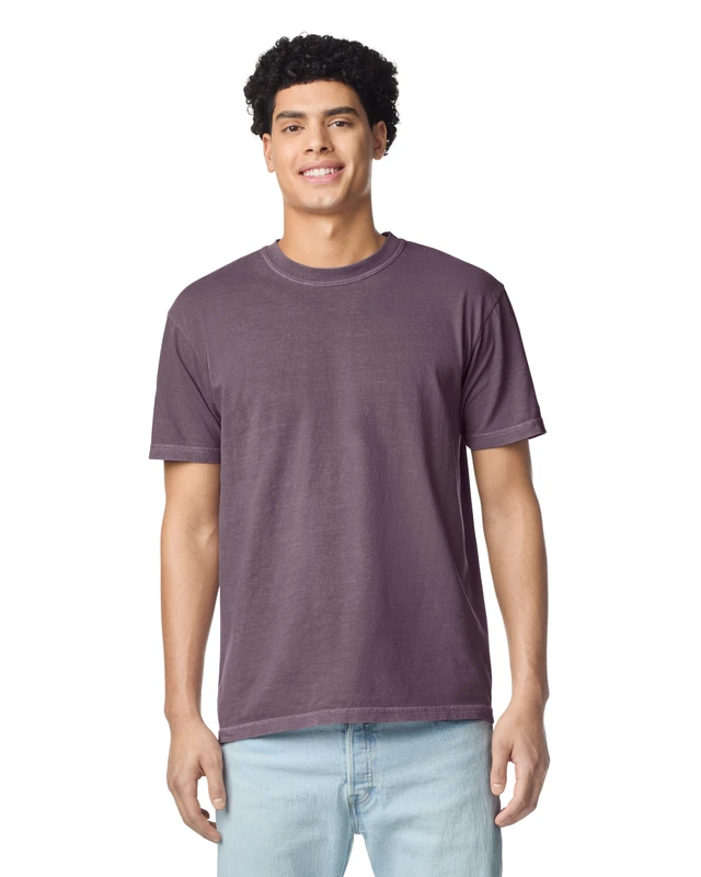 Young man wearing a purple short-sleeve tee and light jeans, smiling at camera.