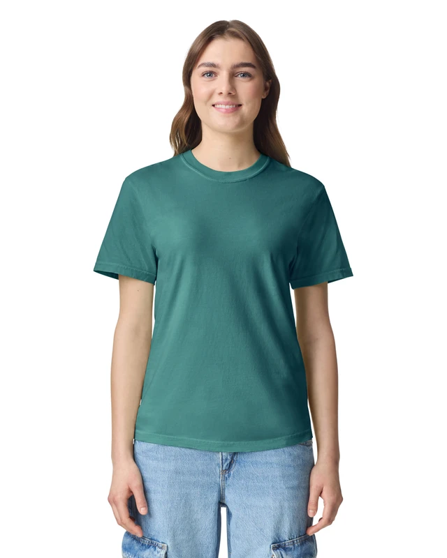 Woman wearing a teal crew-neck T-shirt and light blue jeans, smiling at the camera against a white background.