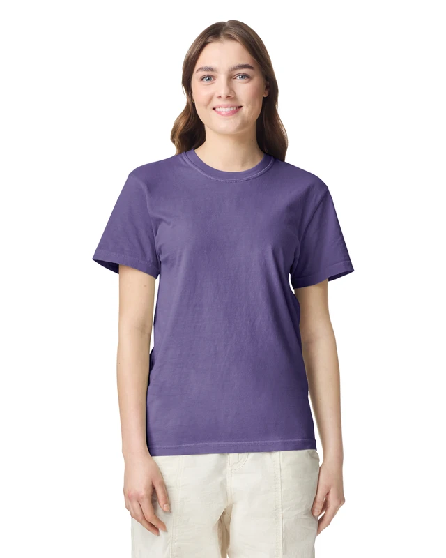 Woman in a purple short-sleeve T-shirt, standing against a white background, smiling at the camera.