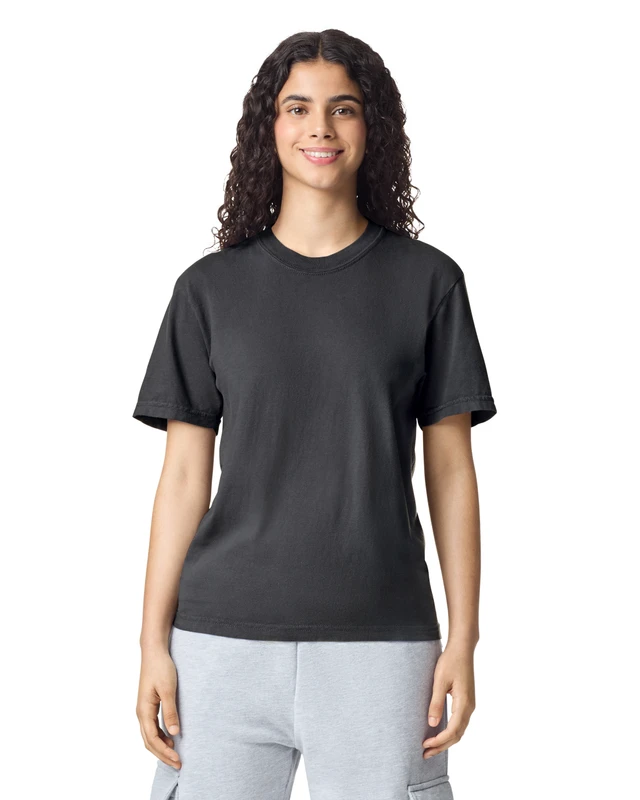 Woman standing and smiling, wearing a black short-sleeve T-shirt and light gray sweatpants, against a white background.