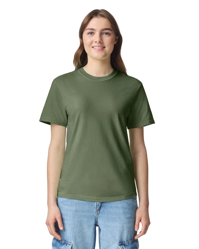 Smiling woman wearing an olive green plain t-shirt and light blue jeans, standing against a white background.