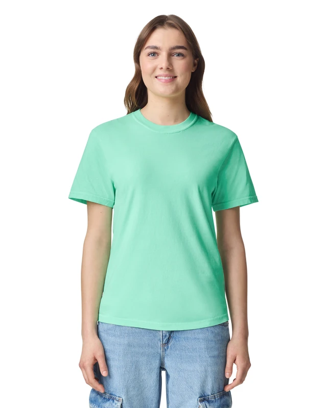 Woman with long brown hair wearing a mint green T-shirt and light blue jeans, smiling at camera on a white background.