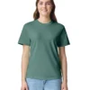 Young woman wearing a teal-green T-shirt and light blue jeans, standing against a white background with a friendly smile.
