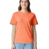 Woman wearing an orange short-sleeve T-shirt and light blue jeans, standing and smiling against a white background.