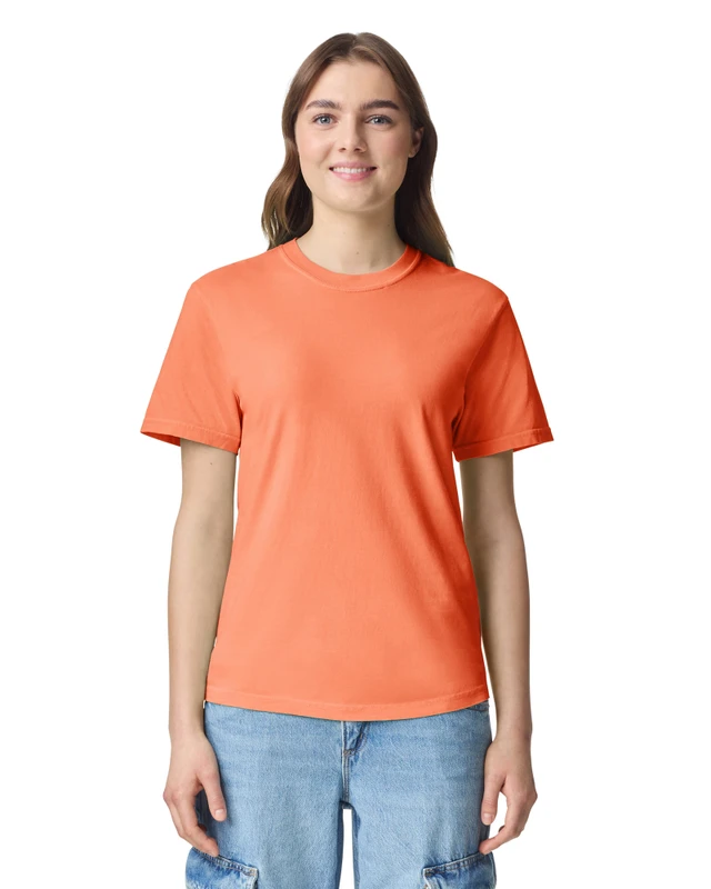 Woman wearing an orange short-sleeve T-shirt and light blue jeans, standing and smiling against a white background.