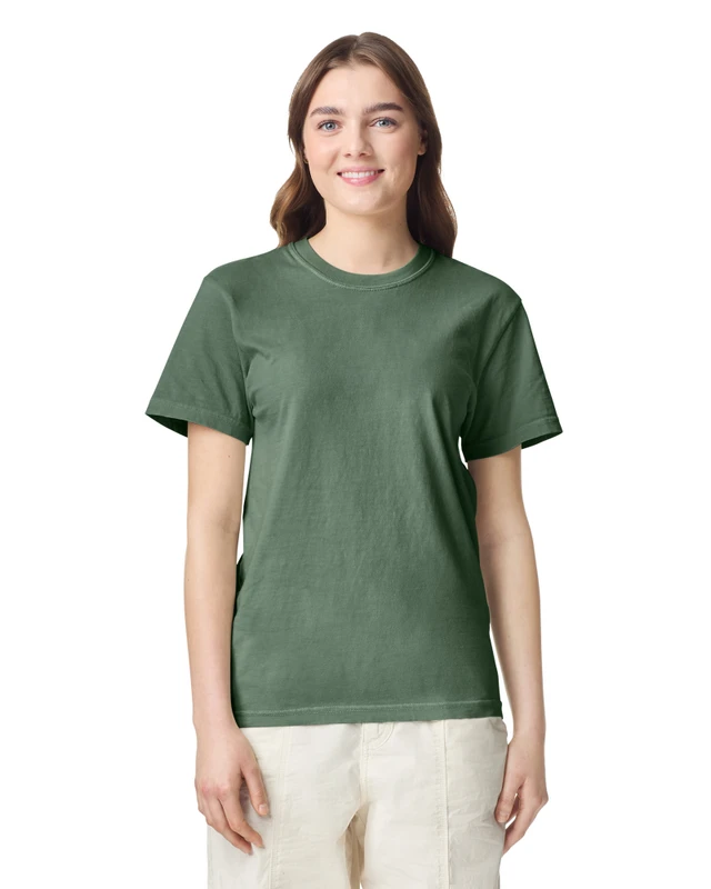 Woman wearing a green crew-neck T-shirt, standing and smiling against a white background.