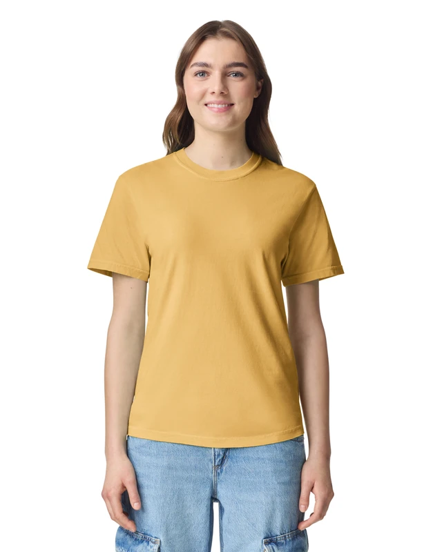 Young woman standing and smiling, wearing a mustard yellow T-shirt and light blue jeans against a white background.