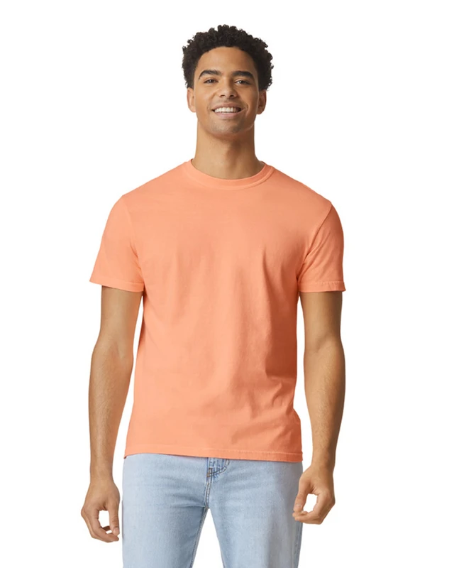 Smiling man wearing a peach T-shirt and light blue jeans, standing against a white background.