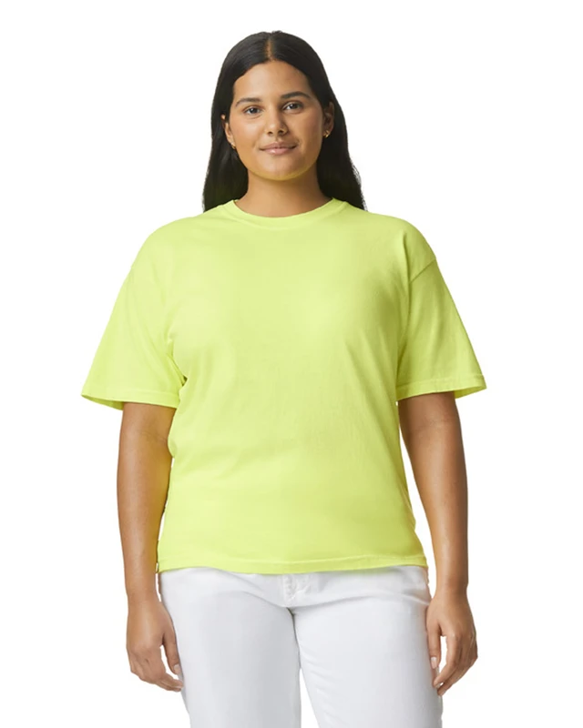 Woman with long dark hair wearing a lime green oversized T-shirt and white pants, facing the camera.