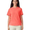 Woman wearing a coral T-shirt and light pants, smiling at the camera against a white background.