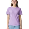 Woman in a lavender T-shirt and blue jeans smiles at the camera against a white background.