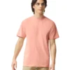 Young man modeling a salmon-pink short-sleeve T-shirt with beige pants, standing and looking off to the side.