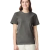 Woman wearing a dark gray T-shirt and light beige pants, standing against a white background.