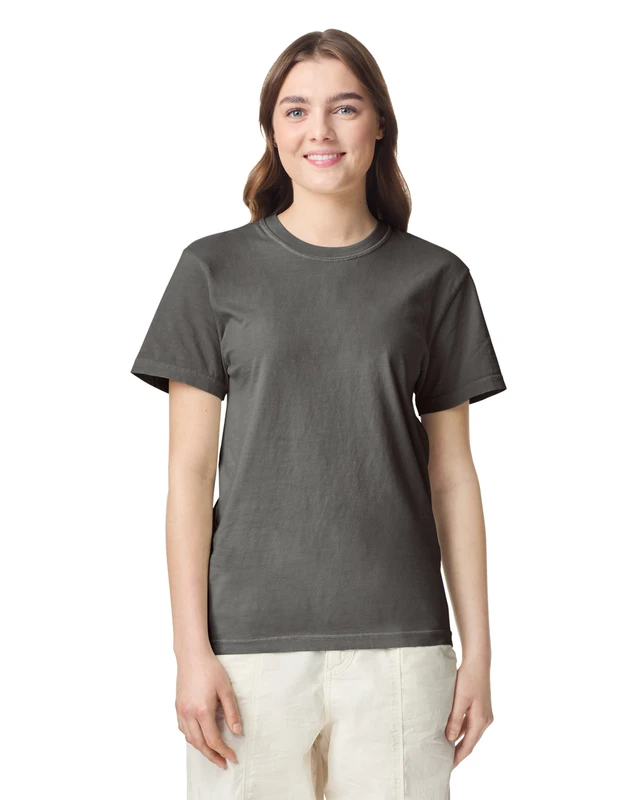 Woman wearing a dark gray T-shirt and light beige pants, standing against a white background.