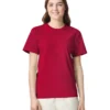 Woman in a plain red crew-neck T-shirt and light pants, smiling against a white studio background.