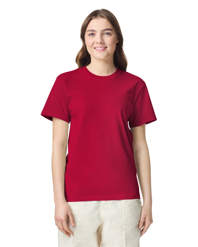 Woman in a plain red crew-neck T-shirt and light pants, smiling against a white studio background.