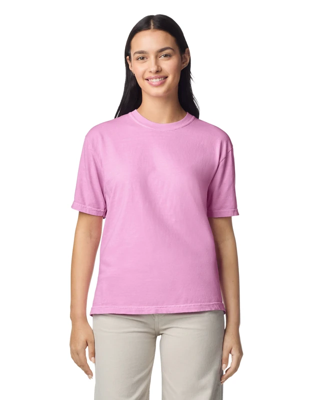 Woman wearing a light pink short-sleeve T-shirt, standing and smiling against a white background.