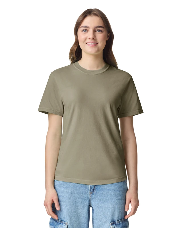 Young woman standing and smiling, wearing an olive green short-sleeve T-shirt and light blue jeans against a white background.