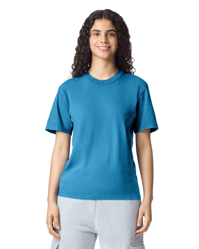 Woman standing and smiling in a blue crewneck T‑shirt and light gray shorts.
