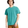 Young man wearing a turquoise short-sleeve T-shirt and brown pants, standing against a white background.