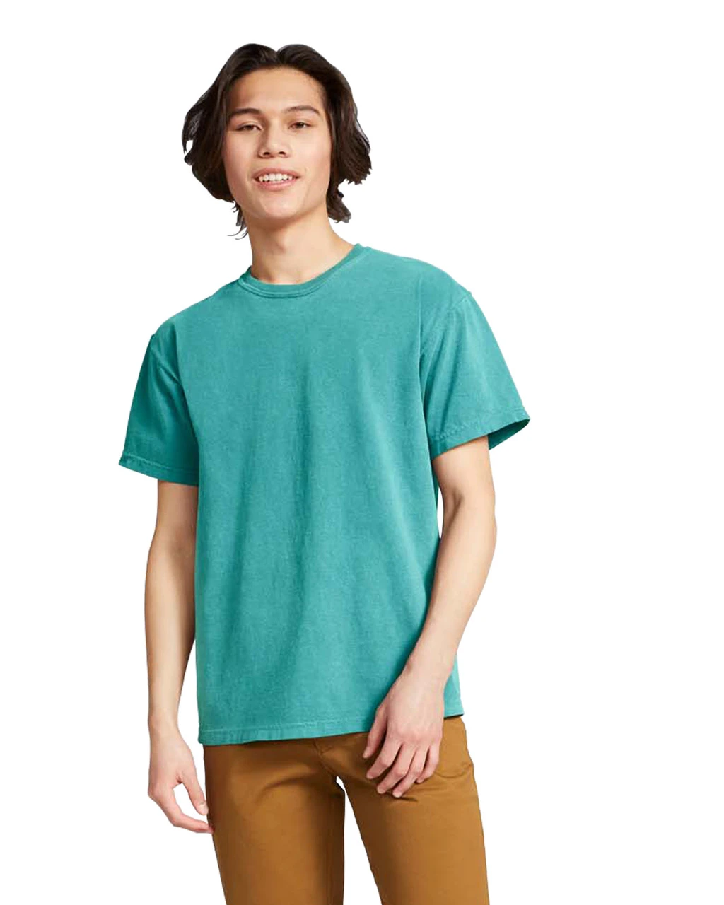 Young man wearing a turquoise short-sleeve T-shirt and brown pants, standing against a white background.