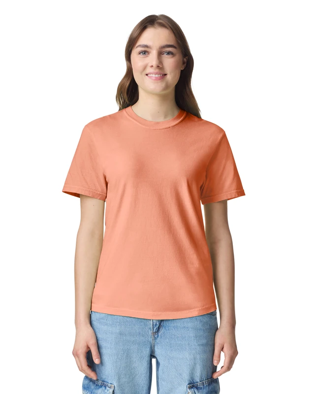 Woman in a peach short-sleeve T-shirt and light blue jeans, smiling at the camera.