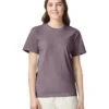 Woman wearing a lavender T-shirt and light pants, smiling at the camera against a white backdrop.