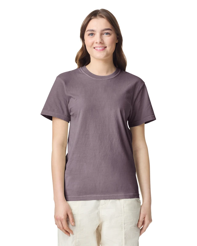 Woman wearing a lavender T-shirt and light pants, smiling at the camera against a white backdrop.