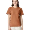 Woman facing the camera, wearing a rust-colored t-shirt and light trousers, smiling warmly.